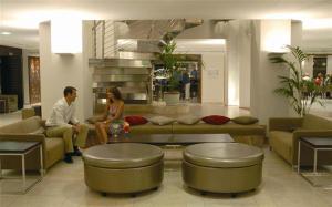 a man and woman sitting on a couch in a lobby at FERGUS Club Font de Sa Cala Beach in Capdepera +50 photos