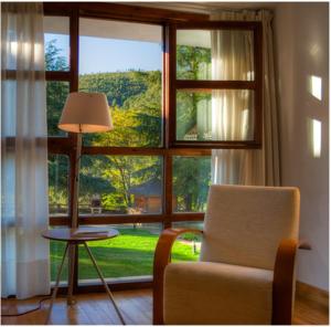 Sala de estar con ventana, silla y mesa en Hospederia Hurdes Reales en Las Mestas