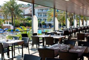 a restaurant with tables and chairs and a pool at FERGUS Club Font de Sa Cala Beach in Capdepera