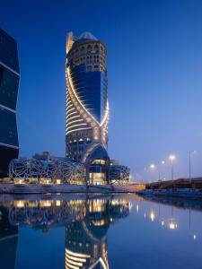 un edificio alto con su reflejo en el agua en Mondrian Doha, en Doha