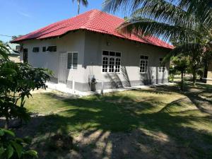 a house with a red roof and a palm tree at Relaxs Homestay in Kota Bharu
