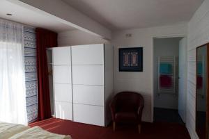 a bedroom with a large white cabinet and a chair at Appartementen Bergen aan Zee de Schelp in Bergen aan Zee
