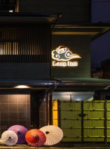 quatro guarda-chuvas em frente a um edifício com um sinal de néon em Laon Inn Gion Nawate em Quioto