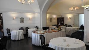 uma sala de jantar com mesas e cadeiras brancas em Palazzo Failla Hotel em Modica