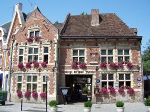 stary ceglany budynek z kwiatami na oknach w obiekcie Auberge Du Bon Fermier w mieście Valenciennes