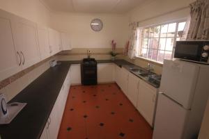 a kitchen with white cabinets and a black counter top at Pin Oak Cottage in Underberg