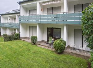 a white building with a balcony and a lawn at Wietheger´s Ferienwohnungen Gästehaus Strycktal II in Willingen +7 photos