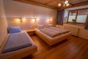 dwa łóżka w pokoju z oświetleniem na ścianie w obiekcie Landhaus KATRIN w mieście Holzgau
