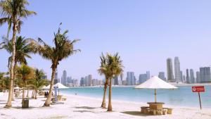 a beach with palm trees and a city in the background at Zain International Hotel in Dubai