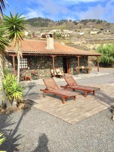 2 bancos de madera en un patio frente a un edificio en Casa rural Los Llanos Negros, en Fuencaliente de la Palma