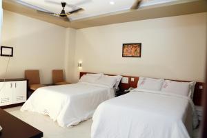 two beds in a hotel room with white sheets at Anandkrishna Residency in Guruvāyūr