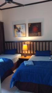 um quarto com 2 camas com lençóis azuis e um candeeiro em Qastury Gold Coast Morib Resort em Morib