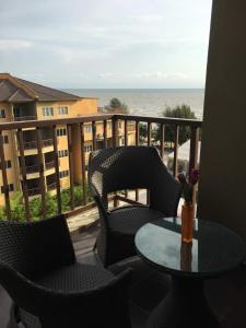 a balcony with chairs and a table with a view of the ocean at Qastury Gold Coast Morib Resort in Morib