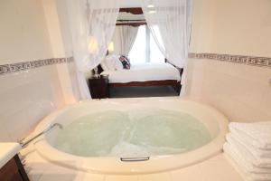 a bath tub in a bathroom with a bedroom at Wine and Roses Bed and Breakfast in McLaren Vale
