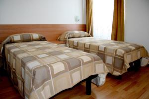 two beds in a room with wooden floors at Pensione Rittmeyer in Trieste