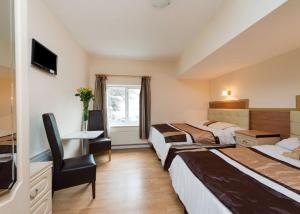 a hotel room with two beds and a desk at Golders Green Hotel in London