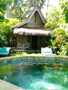 a small house with a swimming pool in front of a house at Kai's Beach House Villa in Gili Air