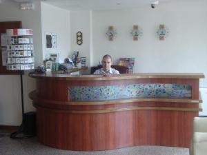 un hombre está sentado en un mostrador en una práctica en Kapri Hotel, en Sofía