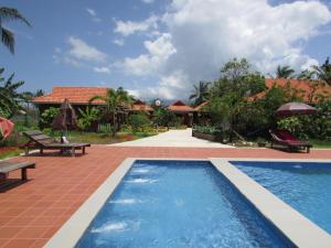 a swimming pool with benches and a house at Phoumrumduol Bungalow in Kampot