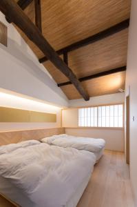 two beds in a room with a wooden ceiling at BenTen Residences in Kyoto