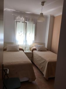 2 Betten in einem kleinen Zimmer mit Fenster in der Unterkunft Apartamento Mirador de Castilnovo in Conil de la Frontera