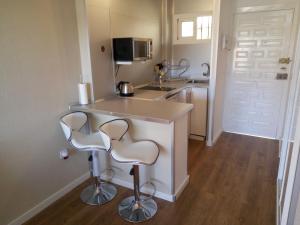 a small kitchen with two bar stools and a counter at Jupiter Sea View in Benalmádena