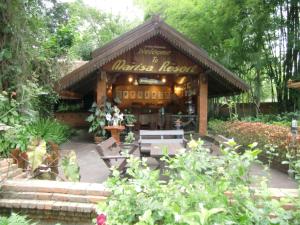 a kiosk in a garden with benches and flowers at Marisa Resort & Spa Chiang Dao in Ban Muang Ngai