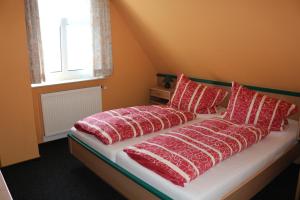 ein Bett mit roten und weißen Kissen und einem Fenster in der Unterkunft Gaststätte Feldkamp in Hinte