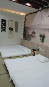 Habitación con 3 camas y una pintura en la pared. en Ji Shih Life Style Hotel, en Tainan