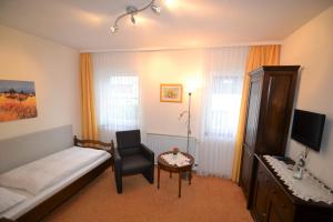 ein Schlafzimmer mit einem Bett, einem Stuhl und einem Tisch in der Unterkunft Hotel Central in Bad Sooden-Allendorf