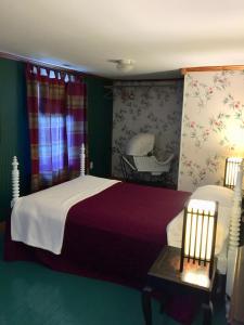 ein Schlafzimmer mit 2 Betten, einem Stuhl und einem Kinderbett in der Unterkunft Dreamweavers Cottages and Home Place Vacation Home in Rustico