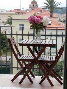 einen Holztisch mit einer Vase aus Blumen auf dem Balkon in der Unterkunft Au Cavettu B&B in Varraze