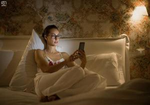 una mujer sentada en una cama mirando un celular en Stella CasaBono, en Sulmona
