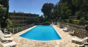 a swimming pool with chairs and a building at Escape to the French Riviera in Villefranche-sur-Mer