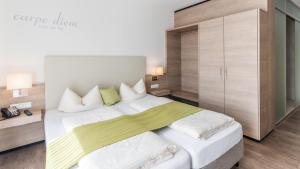 a bedroom with a large white bed with a cabinet at Parkhotel Pfarrkirchen in Pfarrkirchen