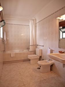 a bathroom with a toilet and a tub and a sink at Hotel Trindade Coelho in Mogadouro