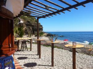 un grupo de mesas en una playa con el océano en Casa Mariana, en Almuñécar