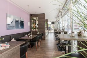 a restaurant with wooden tables and chairs and pink walls at Parkhotel Pfarrkirchen in Pfarrkirchen