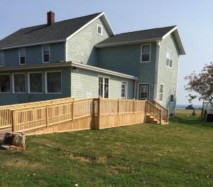 a house with a wooden deck in front of a house at Dreamweavers Cottages and Home Place Vacation Home in Rustico
