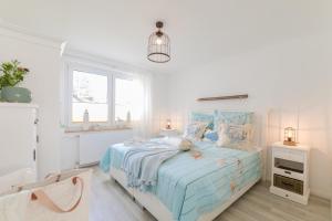a white bedroom with a blue bed with pillows at Boddenhaus Darss in Wieck