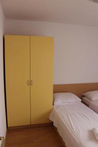 a bedroom with two beds and a yellow cabinet at Apartments Mustač in Drage