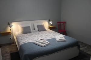 a bedroom with a bed with towels and a red chair at Lost in Terceira in Angra do Heroísmo