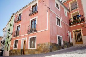 un edificio rosa con ventanas y balcones en una calle en Alojamientos Don Alvaro, en Caravaca de la Cruz