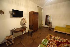 ein Wohnzimmer mit einem Tisch und einem TV an der Wand in der Unterkunft Zù Mariu B&B in Piazza Armerina