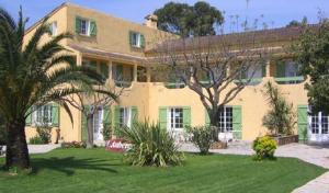 une grande maison jaune avec des palmiers dans une cour dans l'établissement Auberge les Oliviers, à Lucciana