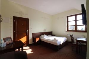 Hotel Marzanna في Niedrzwica Kościelna: غرفة نوم بسرير ومكتب ونافذة