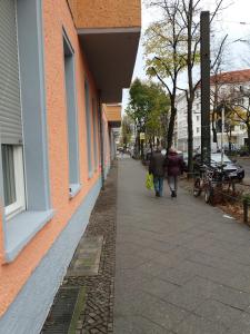 柏林的住宿－費里恩沃農公寓，两个人沿着建筑旁边的人行道走