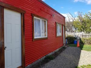 a red building with a white door and two windows at Hostal Aventura Austral in Punta Arenas