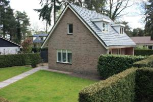 a brick house with hedges in front of it at Het Roodborstje in Otterlo