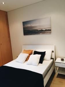 a bedroom with a bed with white and black pillows at NEW APT center 1 min walk beach/river/casino!!! in Figueira da Foz